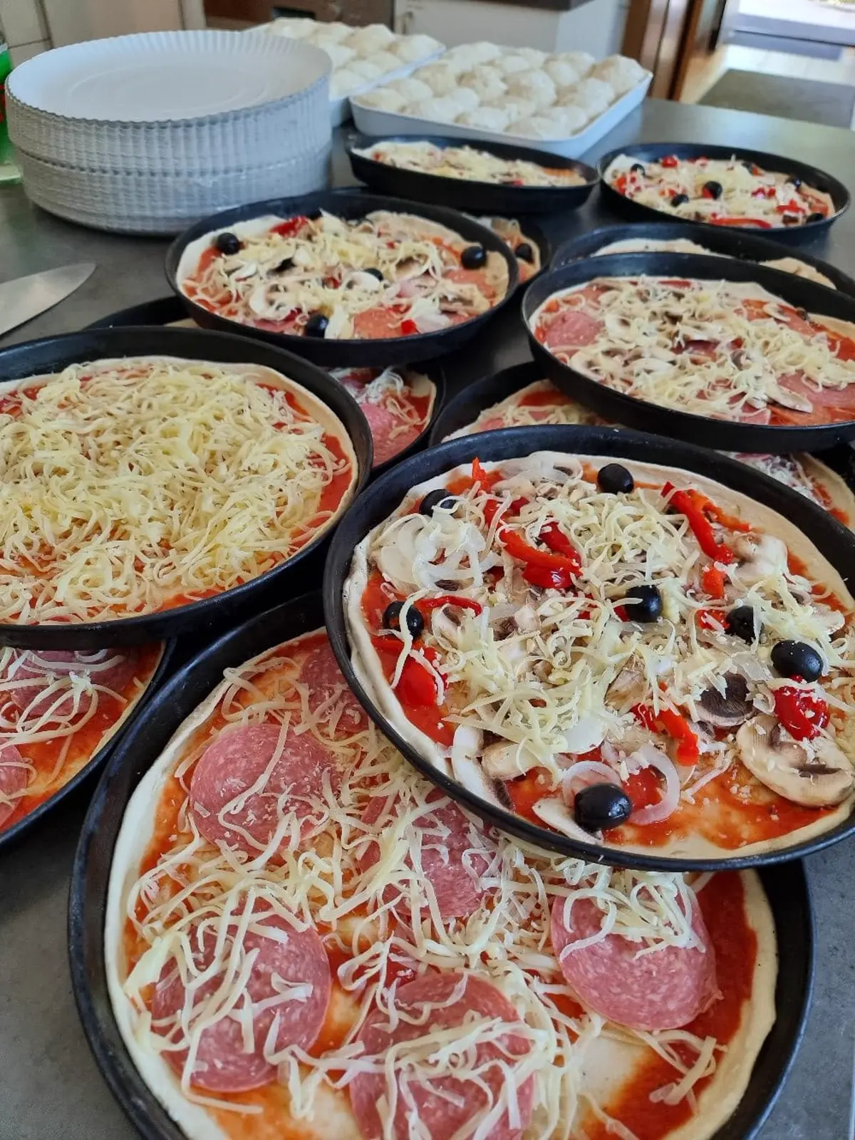 Mehrere frisch gebackene Pizzen auf Blechen
