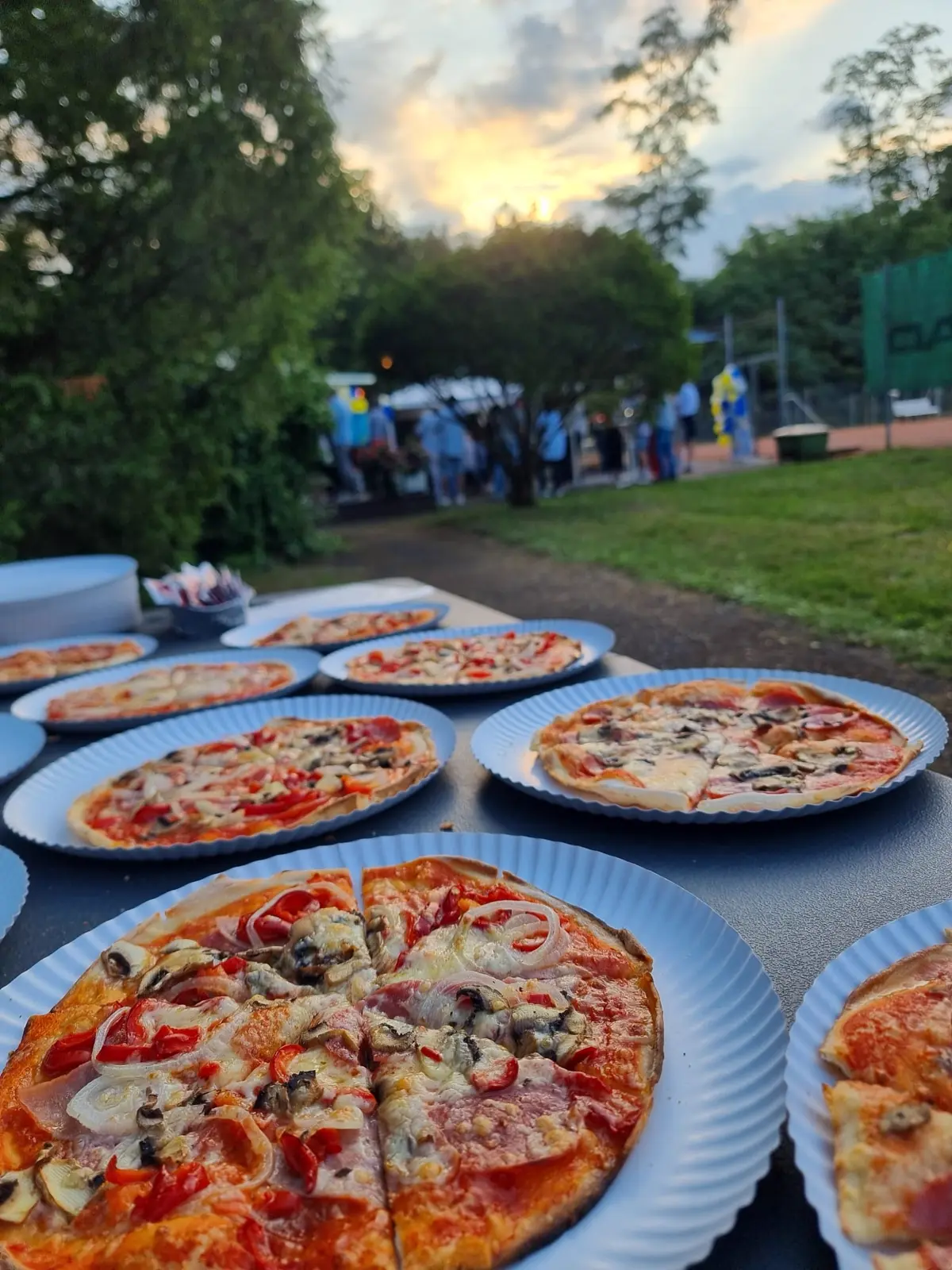 Mehrere fertige Pizzen auf Tellern im Freien